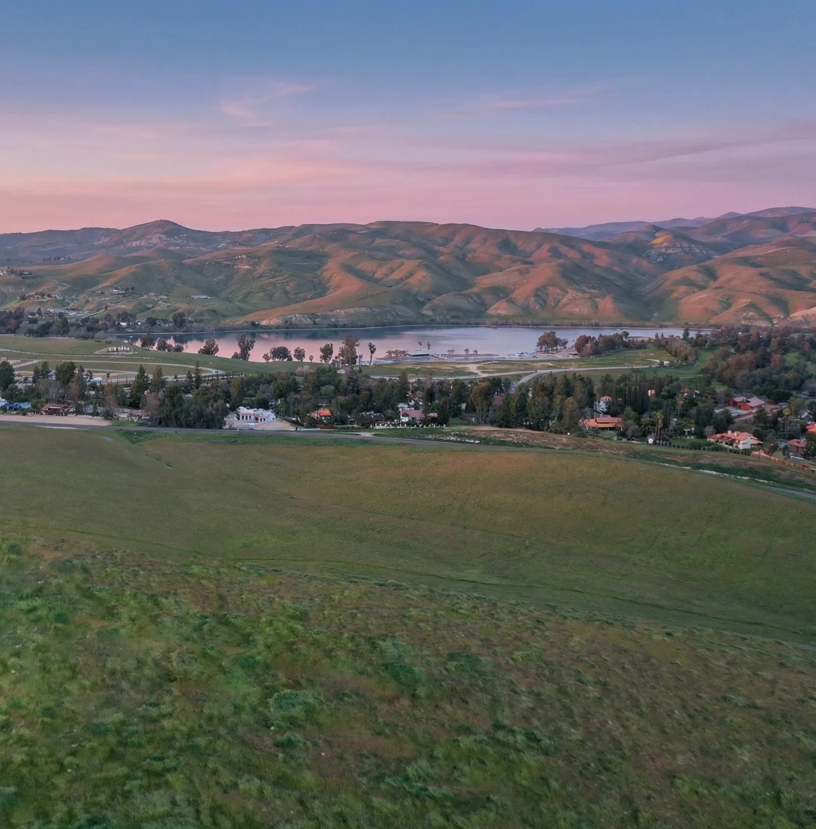 Vista Montaire community at sunset showing the lake, rolling hills, and warm California sky